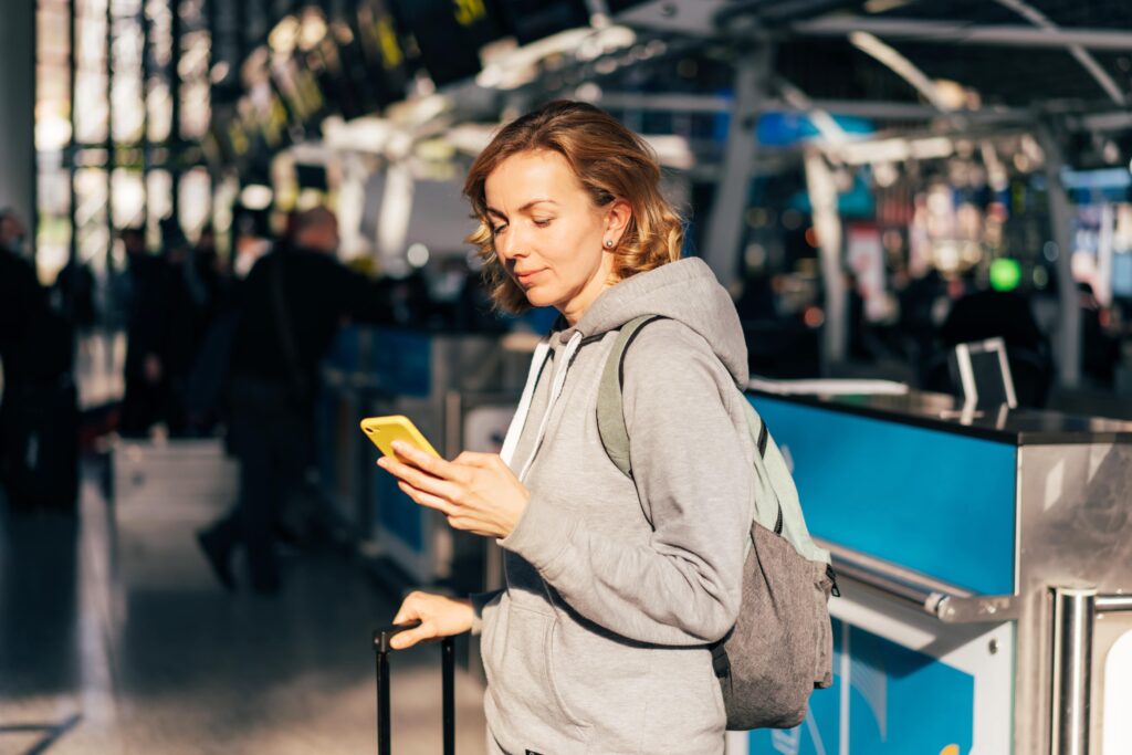 Top 10 Budget Travel Tips - woman checking her phone at the airport