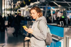 Creating a Travel Itinerary - woman checking her phone at the airport
